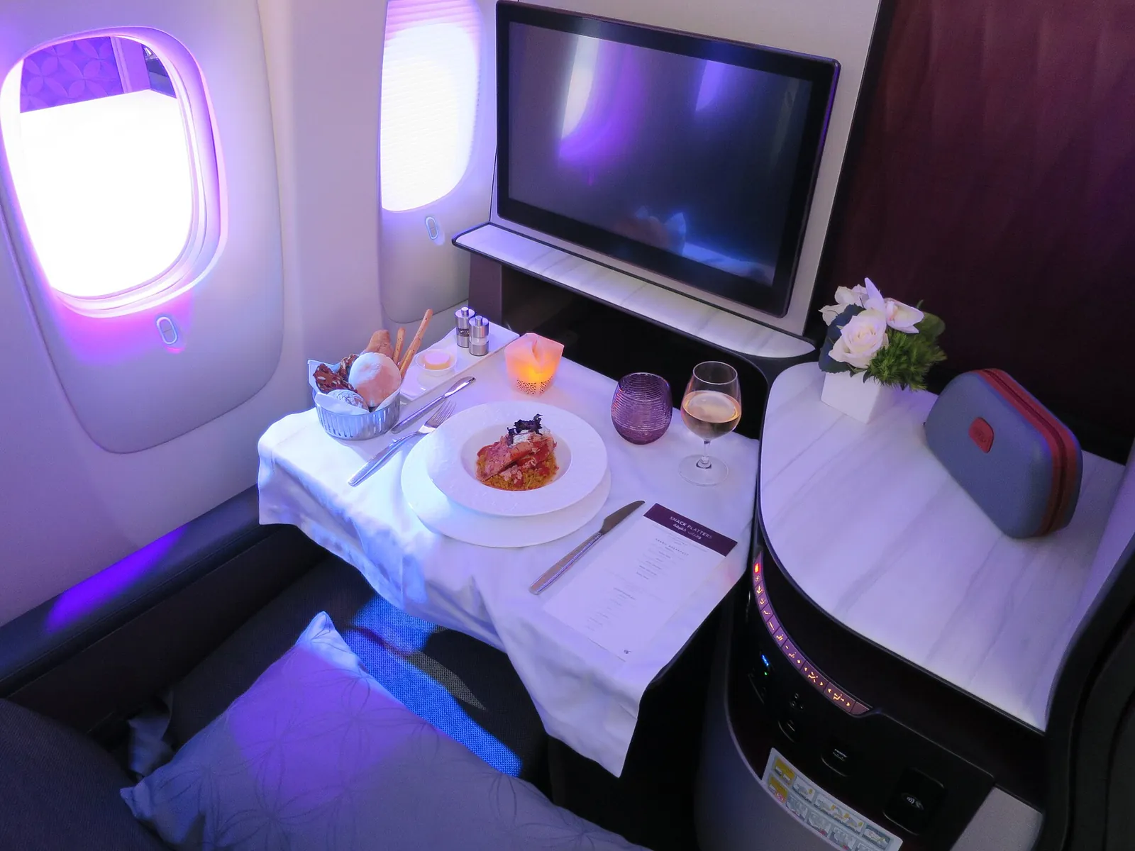 Qsuite da Qatar Airways com jantar servido à mesa ao lado da janela